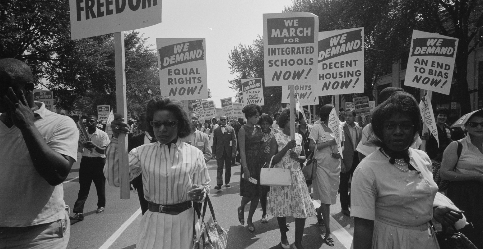 Historic black and white photo of Black women marching for civil rights holding signs demanding equality, education, and housing, symbolising courage and progress.