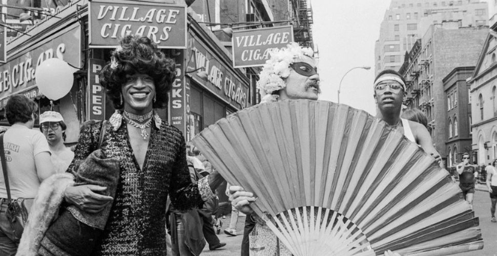 Historic black and white photo of Marsha P. Johnson at a Pride march, celebrating her legacy as a trailblazing activist for LGBTQ+ rights and racial justice.
